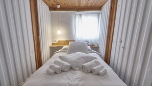 A neatly made bed with white linens and towels, a wooden headboard, and a bedside table with a lamp. - Bungalow - Bolonia Beach Campus Bolonia, your beach house (Tarifa)
