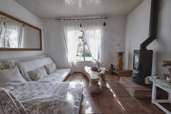 A cozy room with a sofa, a stone table, a television, and a fireplace.