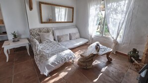 A cozy living room with a sofa, a coffee table, and a mirror. - Bungalow - Bolonia Beach Campus Bolonia, your beach house (Tarifa)
