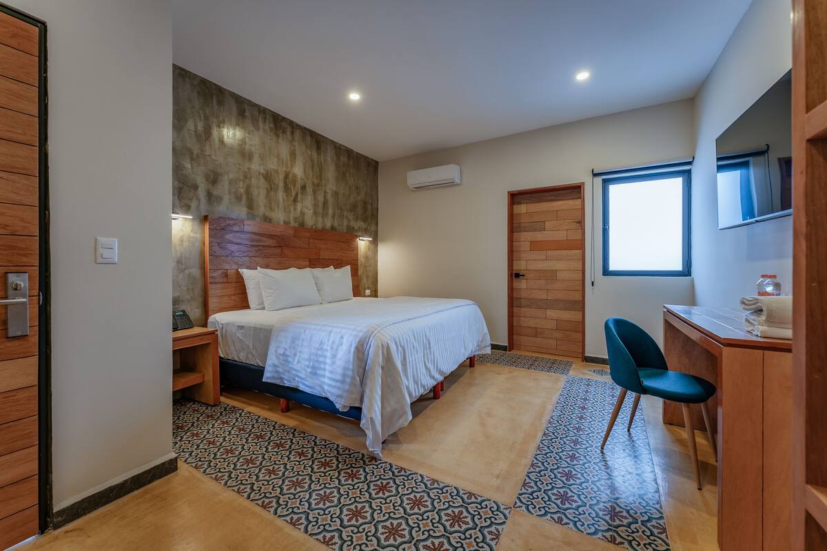 A bedroom with a bed, bedside table, chair, and a desk with a chair.