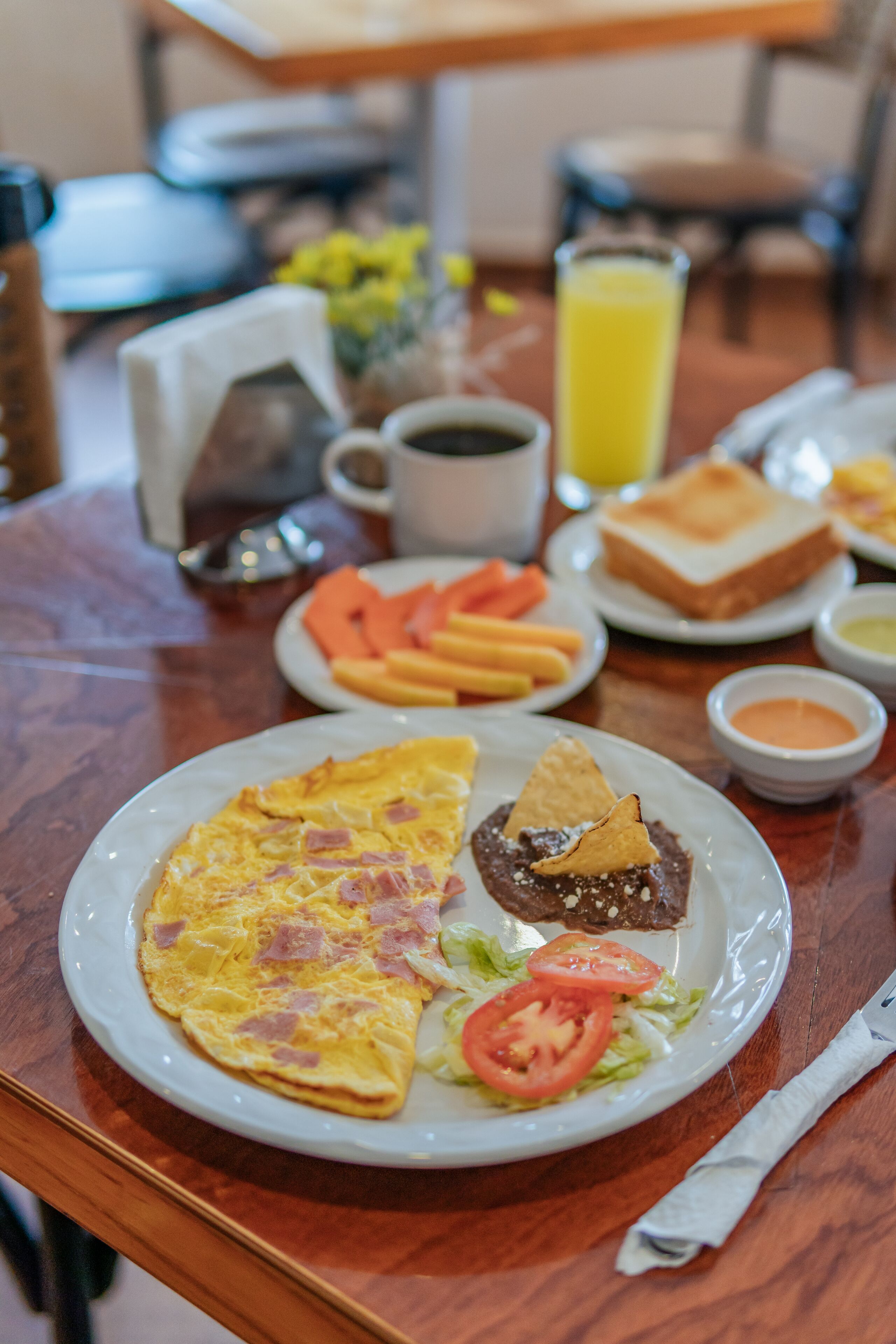 Una mesa de desayuno con platos de comida, incluyendo tostadas, huevos y verduras.
