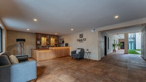 A modern hotel lobby with a reception desk, a sofa, and a chair. - Hotel Casa 57 (Mérida)