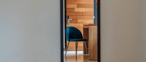 A room with a large mirror reflecting a wooden wall and a blue chair.