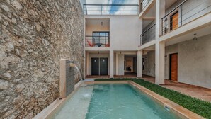 A modern building with a pool, stone walls, and multiple balconies. - Hotel Casa 57 (Mérida)