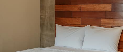 A bed with a wooden headboard, white bedding, and a dark-colored footboard.