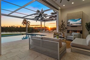 Un espacio exterior moderno con piscina, sillones de descanso y chimenea.