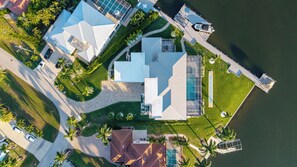 Een woonhuis met een groot zwembad en een steiger die in het water reikt.