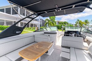 Interior de un barco con zona de estar, una mesa y timón.