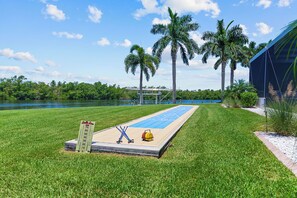 A shuffleboard court with a goal post, a water body, and palm trees in the background. - Villa4dreamers - The ultimate dream on the Gulf of Mexico. (Cape Coral)