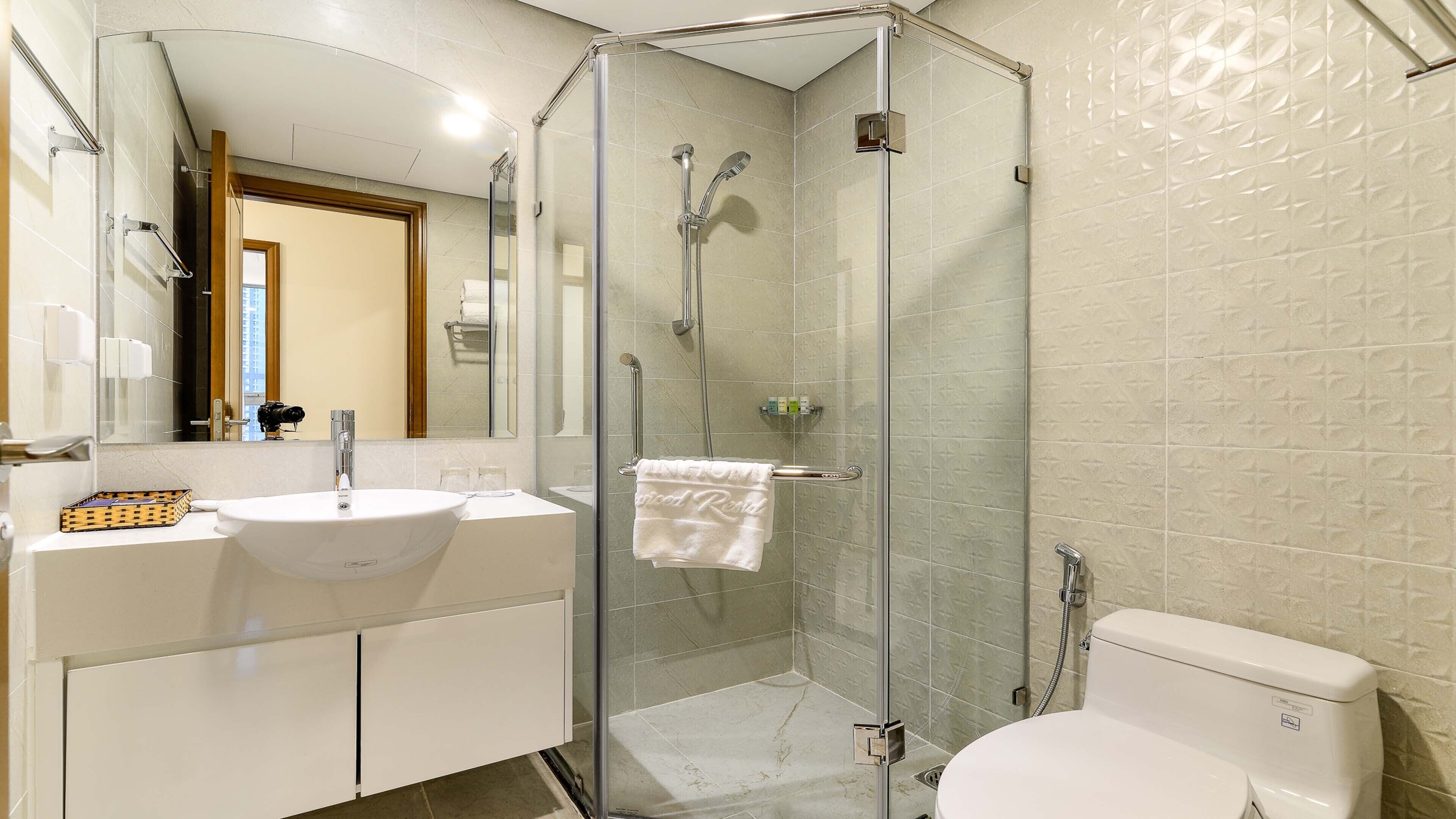 A modern bathroom with a glass-enclosed shower, a white sink, and a toilet.