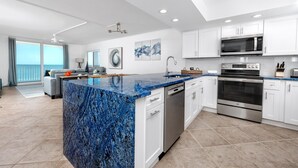Eine moderne Küche mit weißen Schränken, einer blauen Granit-Arbeitsplatte, Edelstahlgeräten und einer großen Kochinsel.