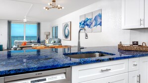 Eine moderne Küche mit blauer Marmorarbeitsplatte, weißen Schränken und einem Geschirrspüler von Bosch.
