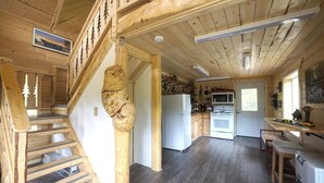 A wooden interior with a staircase, kitchen, and dining area. - Forget Me Not Cabin (Sutton-Alpine)