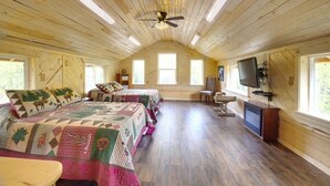 A cozy cabin bedroom with wooden walls, a ceiling fan, a TV, and a fireplace. - Forget Me Not Cabin (Sutton-Alpine)