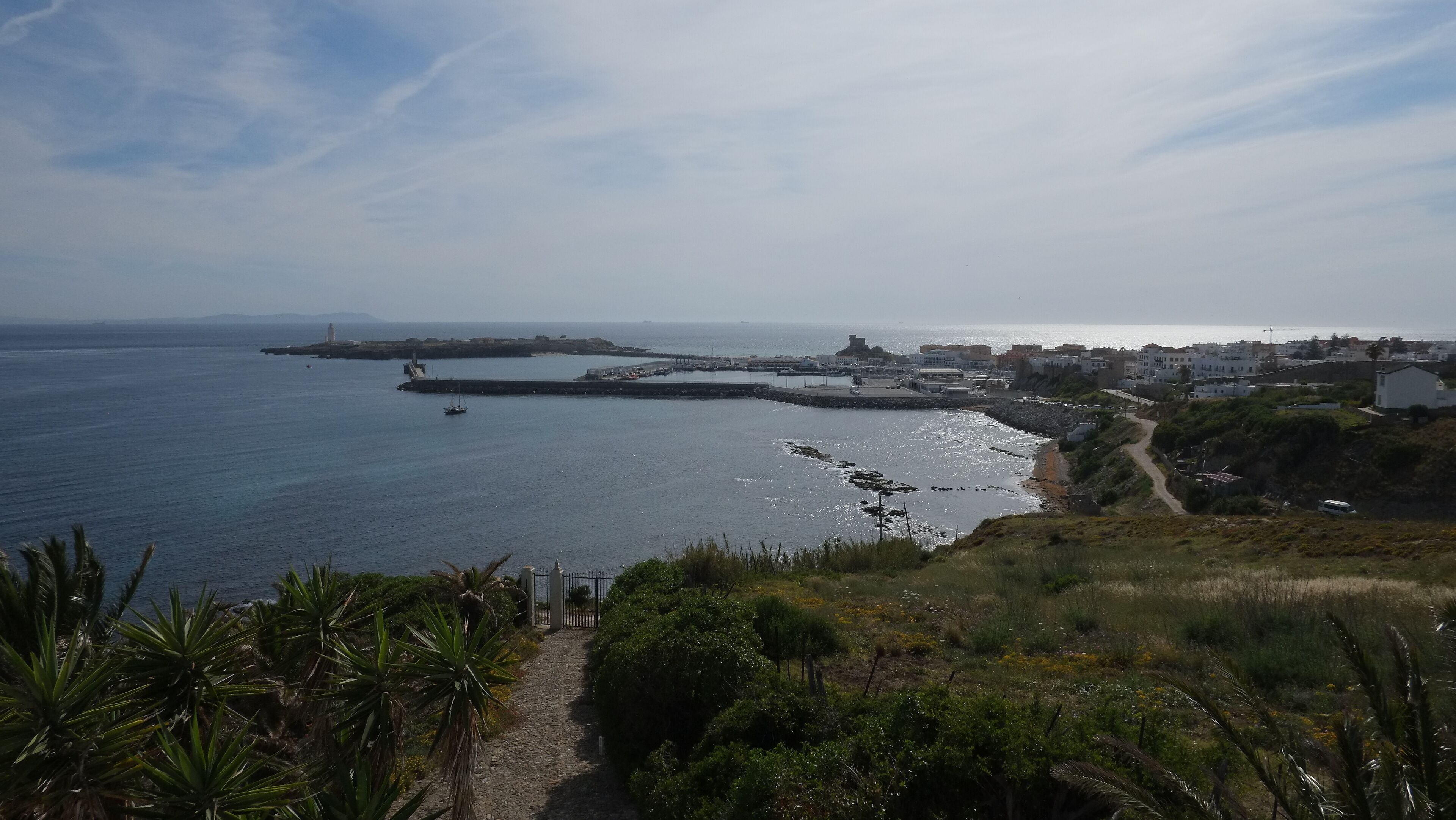 Une ville côtière offrant une vue dégagée sur la mer, avec un phare et un sentier menant à la plage.