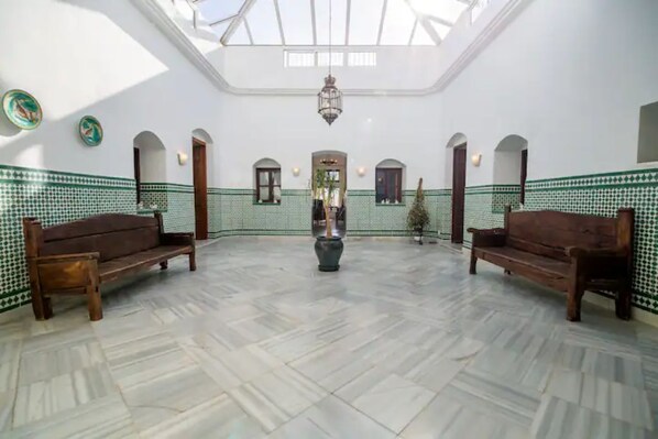 A spacious hall with a high ceiling, patterned walls, and two wooden benches.