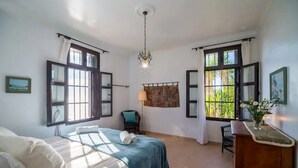 Une chambre à coucher avec un lit, un bureau, une chaise et une fenêtre avec des rideaux.