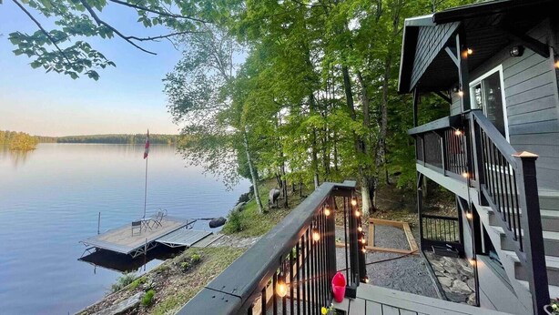 Une propriété au bord du lac, dotée d’un quai, d’une terrasse en bois et d’un bâtiment avec un balcon.