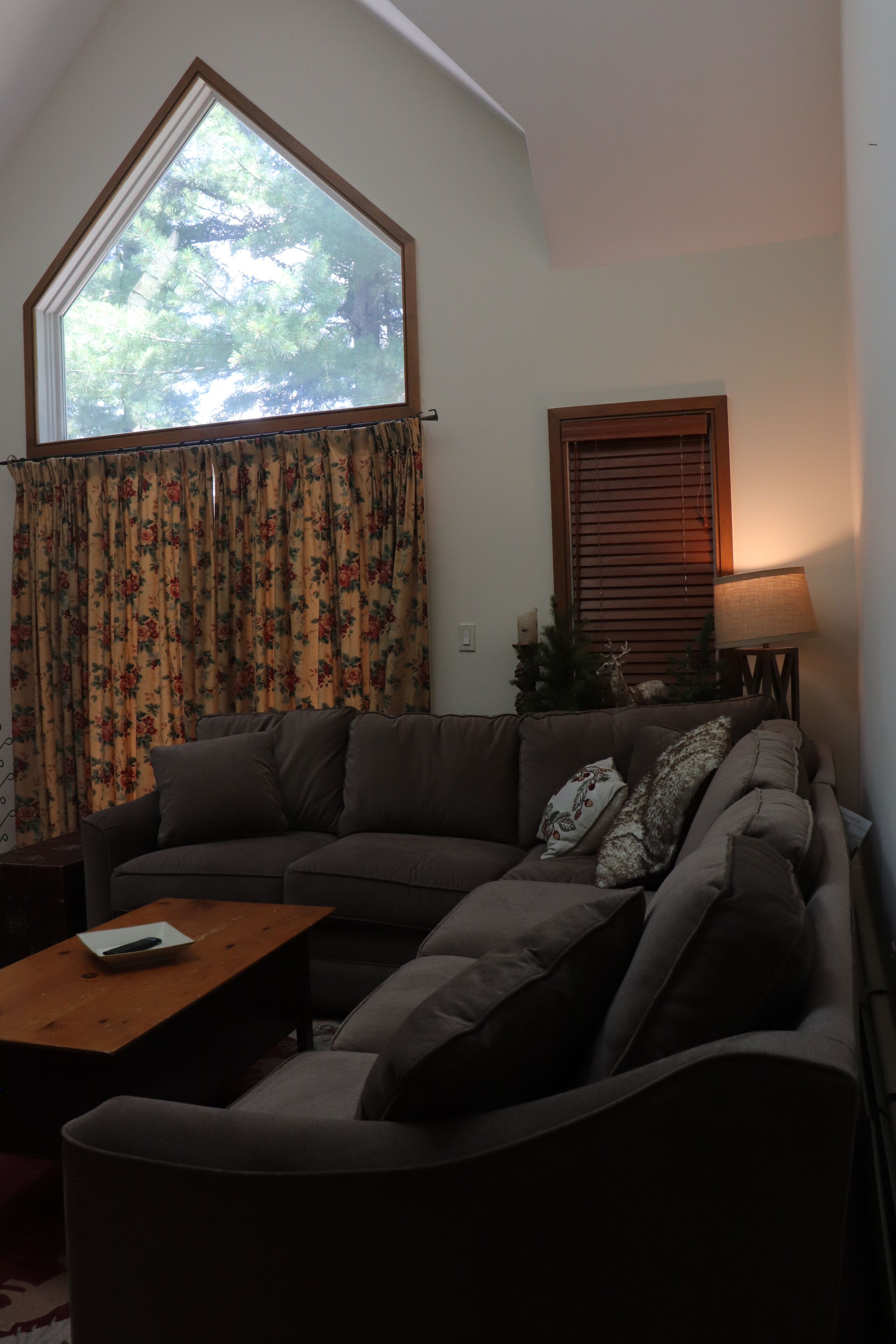 A living room with a large window, a sofa, a coffee table, and a lamp.