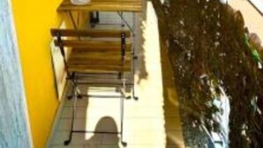 Een smal balkon met een kleine tafel en stoelen, met uitzicht op een gracht met boten.