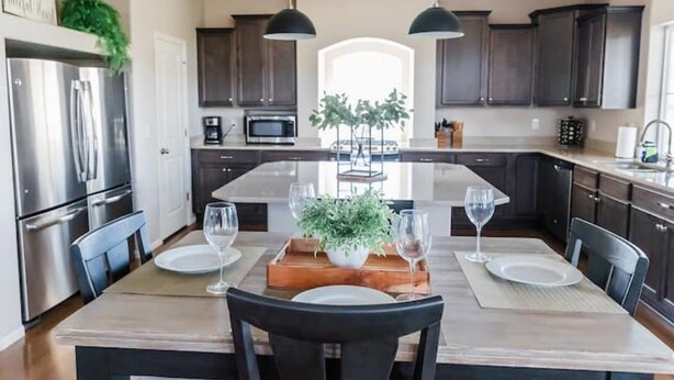 A modern kitchen with dark cabinets, stainless steel appliances, and a central island with seating.