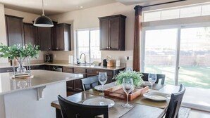 A spacious kitchen with dark wooden cabinets, a large island with a sink, and a dining area with a table set for four.