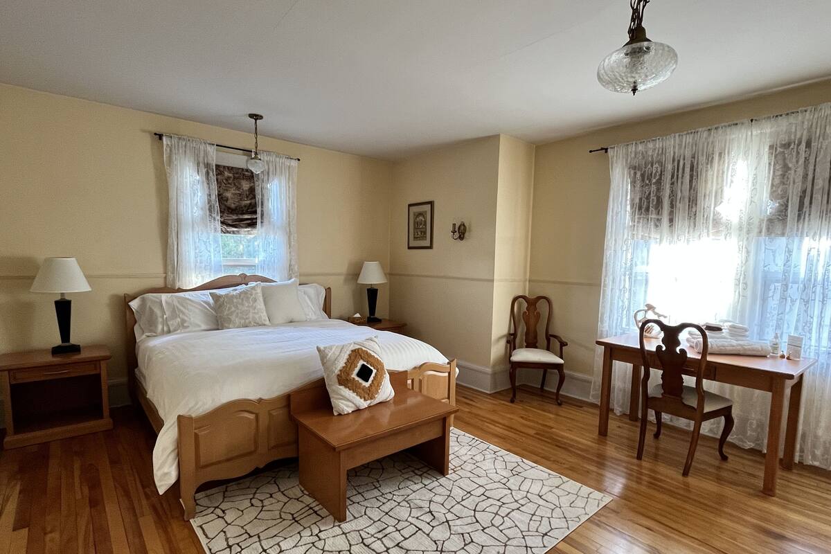 A bedroom with a bed, bedside tables, a desk, and a chair.