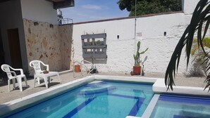 A swimming pool with two white chairs and potted plants. - LA PROVIDENCIA HOTEL (Neiva)