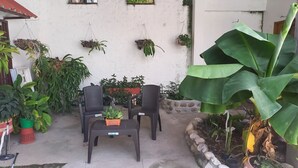 A patio area with two black plastic chairs, a small table, and various potted plants. - LA PROVIDENCIA HOTEL (Neiva)