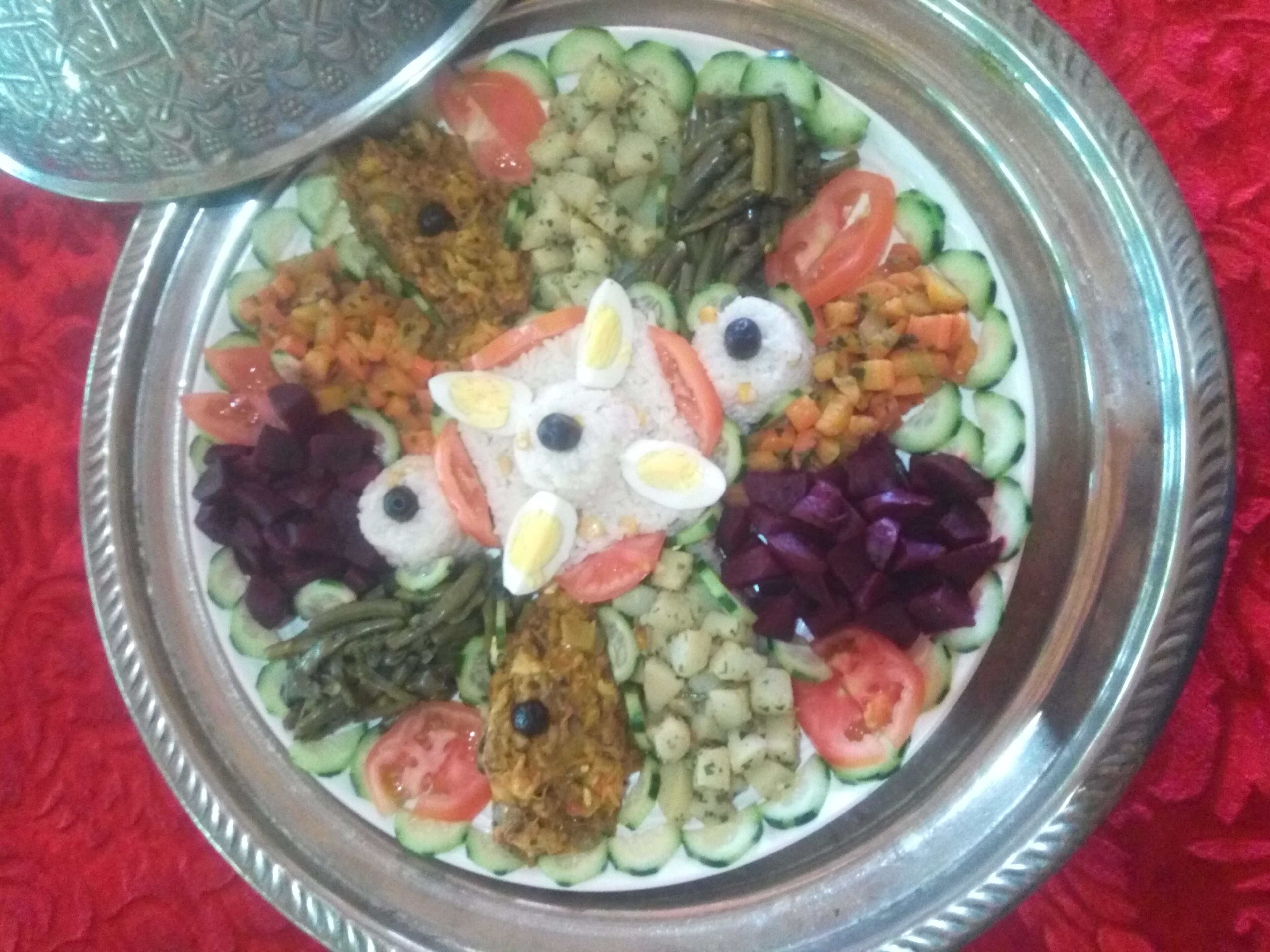 A traditional dish arranged on a silver platter with various vegetables and eggs.
