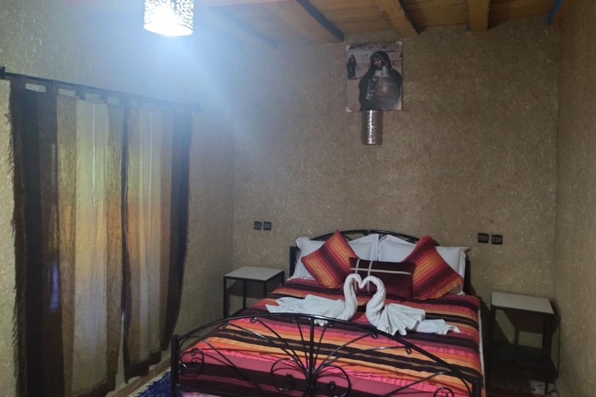 A room with a bed, a wall-mounted picture, and a hanging light fixture.