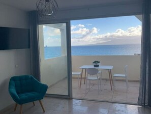 Enjoy the serene sea views from your balcony, featuring a table and chairs, and unwind in the comfort of your stylish room with a wall-mounted TV.