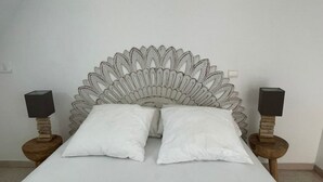 A bed with a unique feather-like headboard, two bedside tables with speakers, and white pillows.