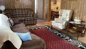 Una sala de estar acogedora con un sofá a cuadros, un sillón floral y una alfombra estampada en rojo.