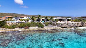A coastal resort with clear turquoise waters, white buildings, and palm trees.