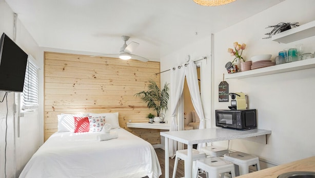 Una habitación de hotel pequeña con cama, un escritorio, microondas y televisor.