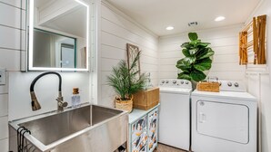 A laundry room with a sink, a mirror, a washing machine, a dryer, and a large plant. - Private Pool & Dock: Old Florida Waterfront Home (Hernando Beach)