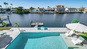 A swimming pool with clear water, surrounded by lounge chairs and a dock. - Private Pool & Dock: Old Florida Waterfront Home (Hernando Beach)