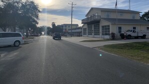 A street with a building that has a garage and a balcony. - Sailor's Choice - NON SMOKING Apartment in Downtown Cedar Key with Gulf Views!
 (Cedar Key)