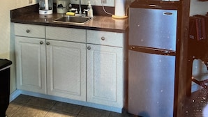 A kitchen with white cabinets, a refrigerator, a microwave, and a coffee maker. - Sailor's Choice - NON SMOKING Apartment in Downtown Cedar Key with Gulf Views!
 (Cedar Key)