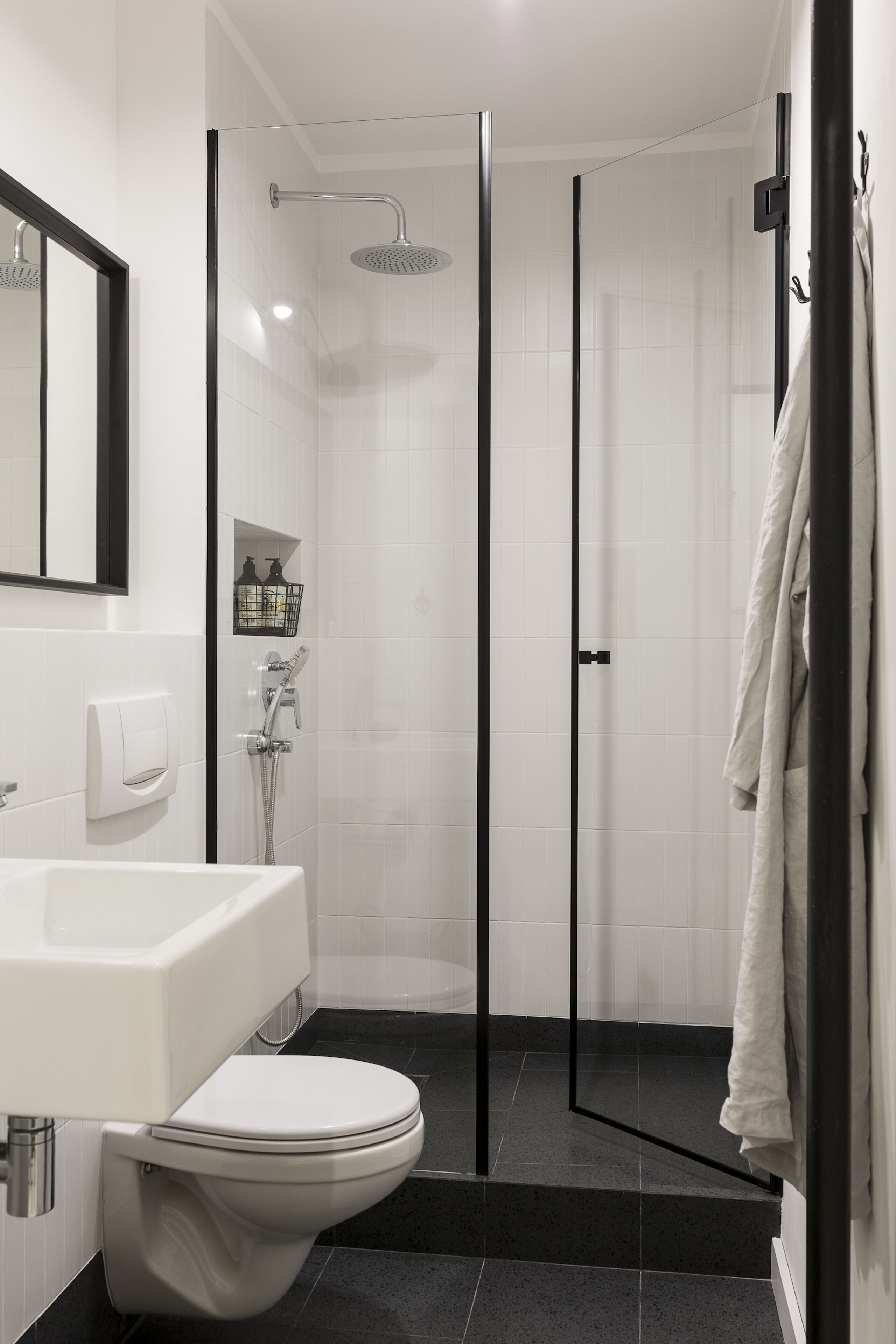 A modern bathroom with a glass-enclosed shower, a white sink, and a toilet.