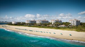 A beachfront hotel with multiple white buildings, a sandy beach with umbrellas, and clear turquoise waters. - Beautiful Marriott Ocean Point Resort - Studio Villa - on the beach. (Palm Beach Shores)