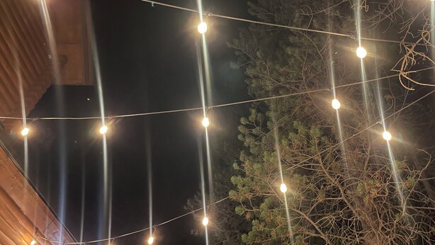 Guirnalda de luces sobre un cielo oscuro, con un árbol en primer plano.