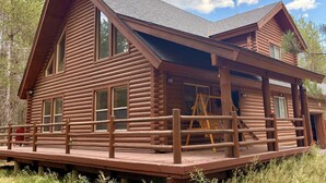 A log cabin with a porch, large windows, and a chimney.