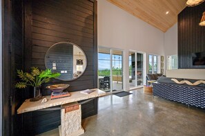 A modern interior with a stone countertop, a round mirror, and a view of the outdoors through large sliding glass doors.