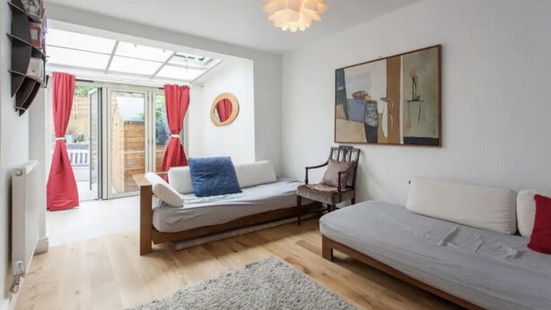 A modern bedroom with a bed, a chair, a sofa, a large window with curtains, and a ceiling light fixture. - Modern Bright Shoreditch 2-bed Apartment in London (London)
