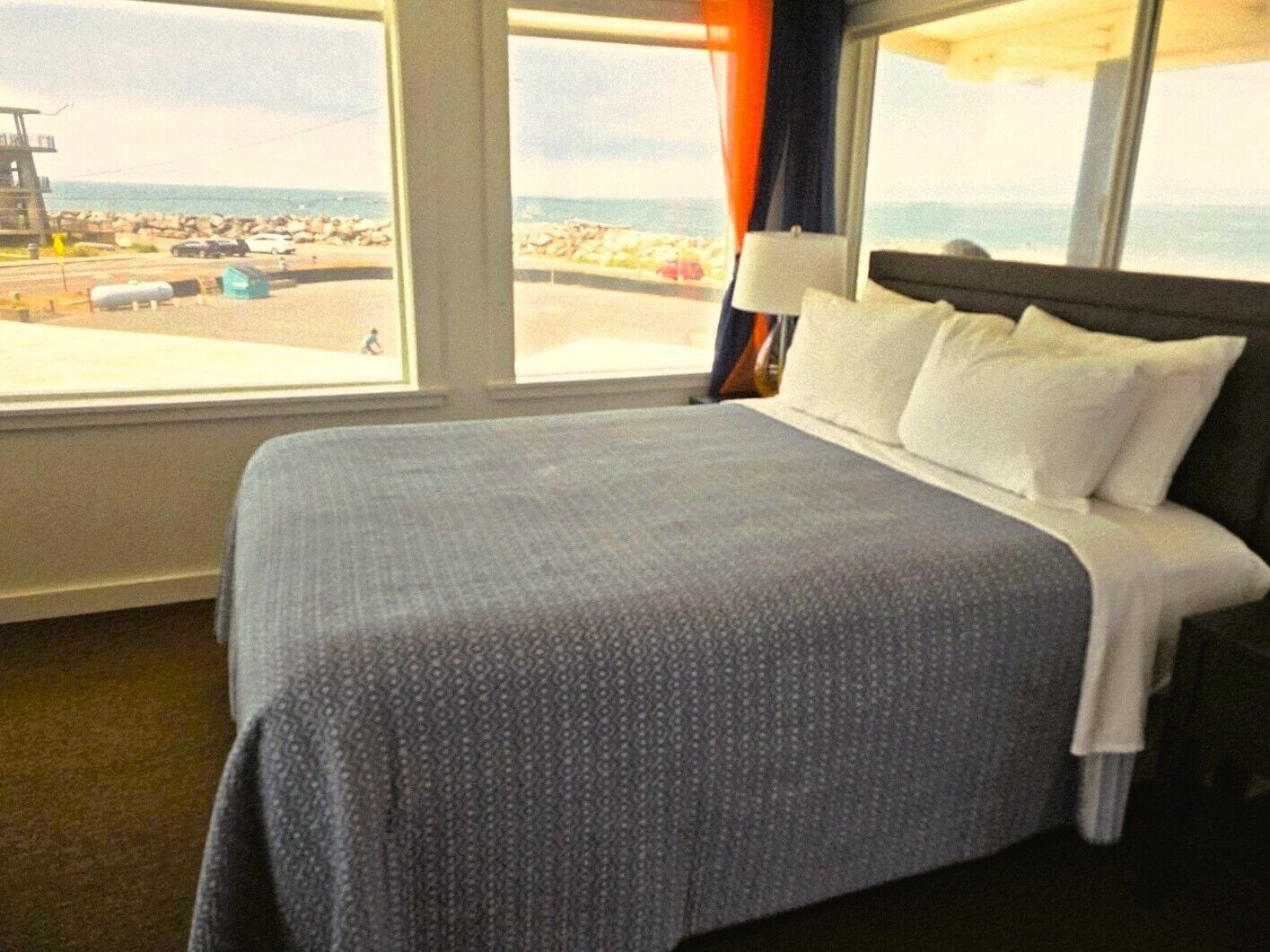 Une chambre d’hôtel avec un lit, de grandes fenêtres et une vue sur la plage.