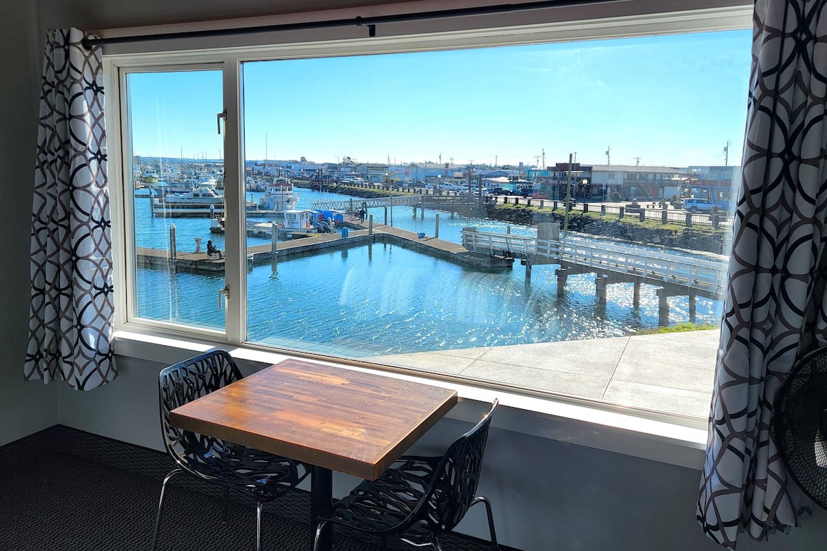A room with a large window overlooking a marina with boats and docks.