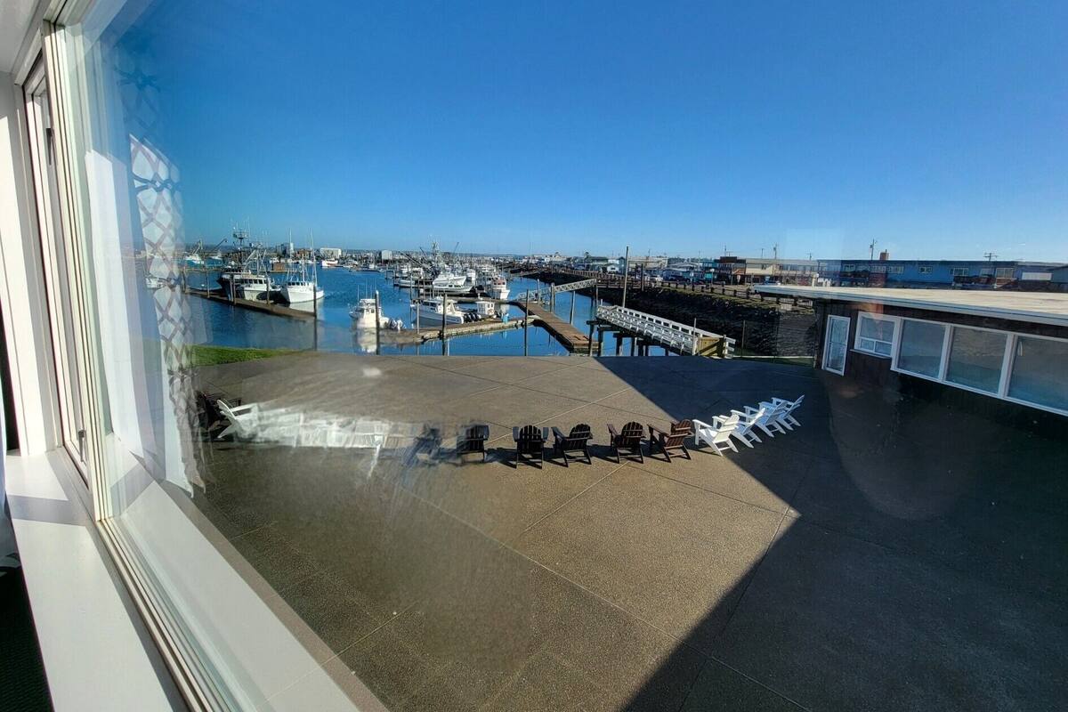 A view of a marina with boats docked, a bridge, and a clear sky.