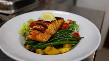 A plate of grilled salmon with asparagus and pineapple, garnished with a lemon wedge.